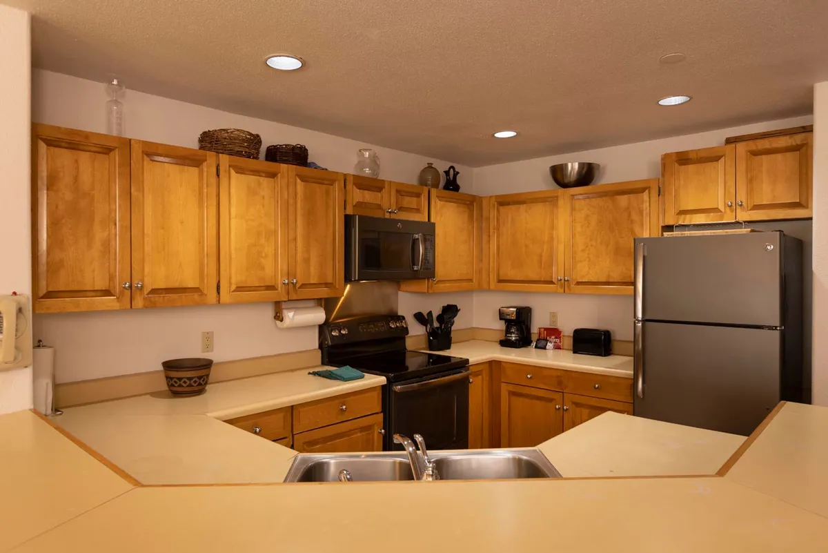 A homey kitchen with wooden cabinetry, stainless steel appliances, and a central kitchen island. The space is ideal for cooking, entertaining, and family gatherings, evoking the ambiance of holiday traditions and intimate dinners.