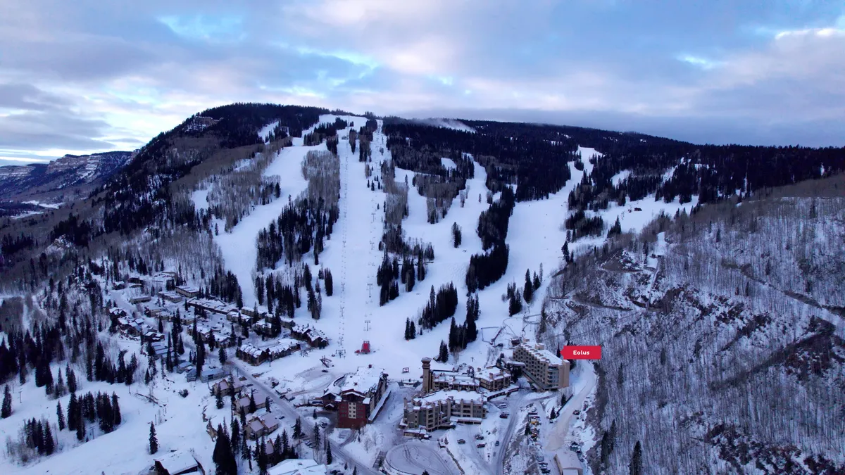 This exterior image captures the ski slopes of Purgatory Resort with resort buildings nestled among snow-dusted trees and a stunning mountain backdrop. The scene is animated by skiers and snowboarders, evoking the thrill of alpine adventure and the tranquility of mountain surroundings.