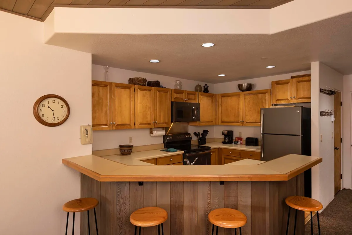 A cozy, inviting kitchen featuring a kitchen island, wooden cabinets, and stools. The scene is set for cooking or socializing, with a family baking cookies together, highlighting the kitchen's potential for both meal preparation and togetherness.